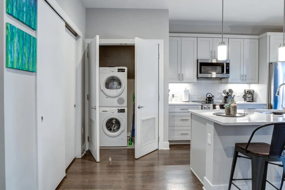 A stylish kitchen and laundry area with sleek appliances and bar stools, blending practical amenities with spaces for casual conversations. The design is contemporary, making it easy for families and friends to prepare meals or gather before heading out.