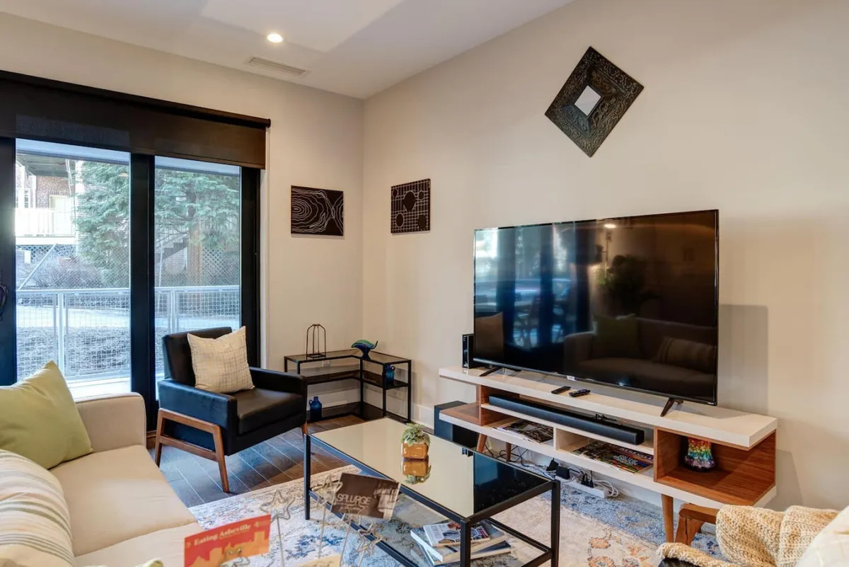 A comfortable living area with a plush sofa, coffee table, television, and distinctive artwork on the walls. This space suggests a cozy environment for socializing, unwinding after business activities, or preparing for a day in the city.